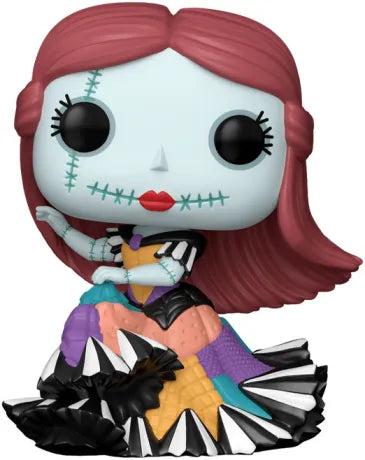 Funko Pop! L’Étrange Noël de Monsieur Jack – Sally (N°1605). Figurine de Sally en robe colorée cousue, cheveux rouges et peau bleue, assise avec élégance, fidèle au style Tim Burton.
