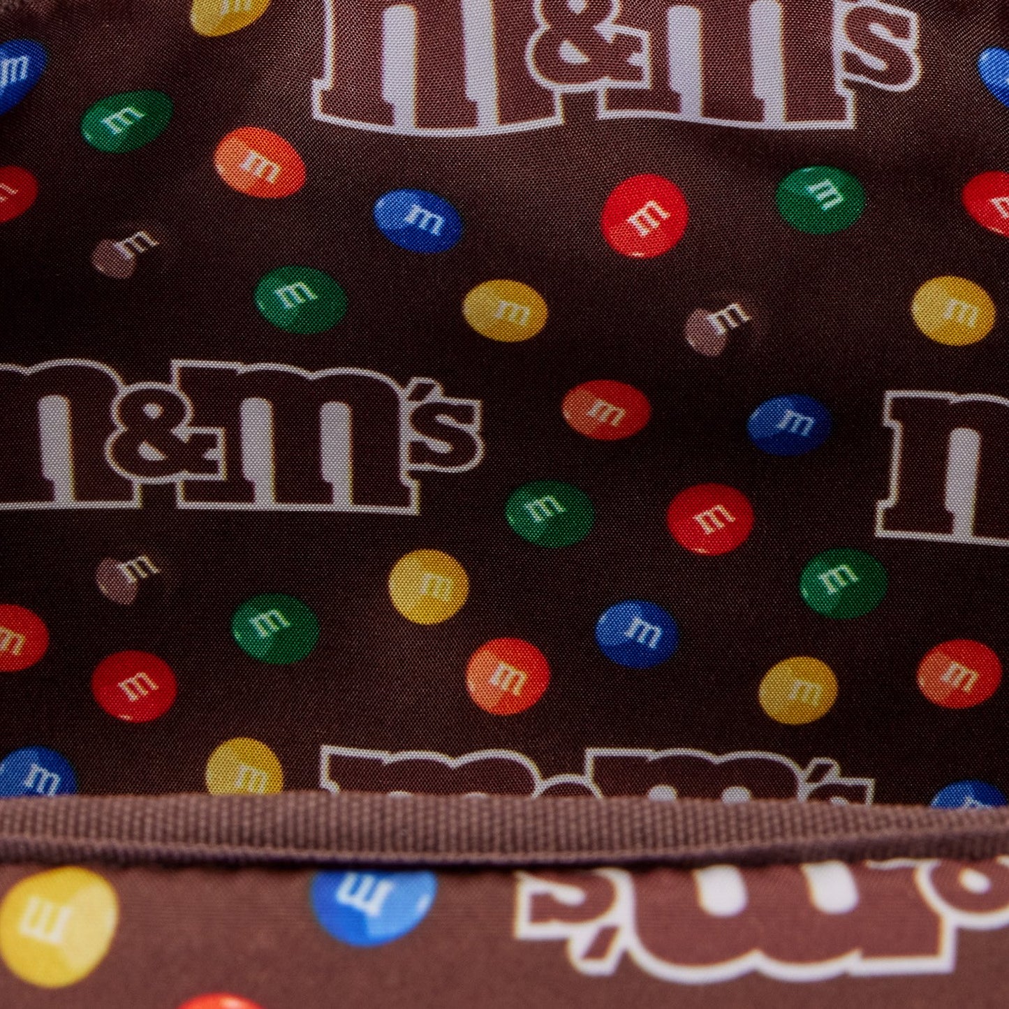 Sac à bandoulière Loungefly M&M’s avec porte-monnaie. Design chocolat embossé avec pastilles colorées et doublure intérieure exclusive. Accessoire collector parfait pour les fans de M&M’s.
