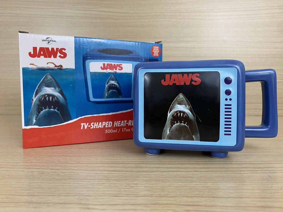 Mug rétro TV thermoréactif – Les Dents de la Mer (Jaws) – 500 ml – Officiel. Mug en céramique en forme de télé rétro, avec effet thermoréactif révélant le requin culte. Un must-have pour les fans de Spielberg et cinéma d’horreur.