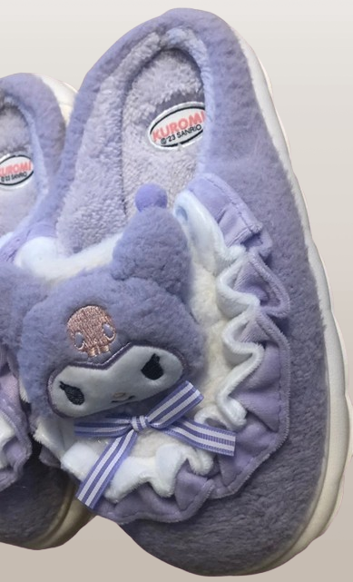 "Chaussons Kuromi – Sanrio – Design Doux et Kawaii. Ces chaussons violets en peluche présentent l'espiègle Kuromi avec des détails en ruban et des volants, offrant confort et style pour tous les fans de l'univers Sanrio !"

