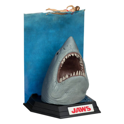 Figurine JAWS – Les Dents de la Mer – 50ème Anniversaire – Movie Maniacs 16 cm. Représentation du requin attaquant une nageuse, avec socle et décor collector. Une pièce incontournable pour les fans de cinéma culte.