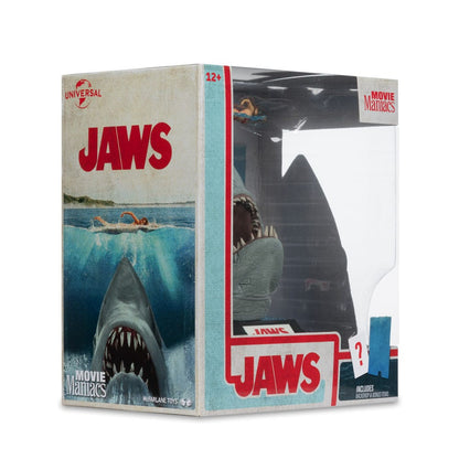 Figurine JAWS – Les Dents de la Mer – 50ème Anniversaire – Movie Maniacs 16 cm. Représentation du requin attaquant une nageuse, avec socle et décor collector. Une pièce incontournable pour les fans de cinéma culte.