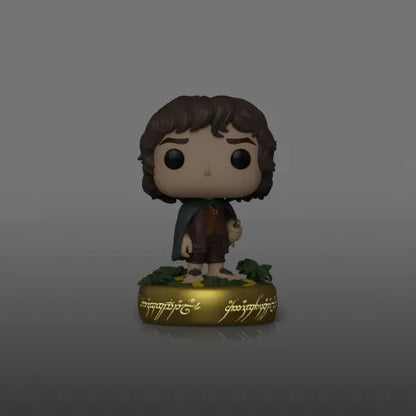 Funko Pop! Le Seigneur des Anneaux – Frodon Sacquet (N°1832, Glow in the Dark). Figurine exclusive avec socle doré orné des inscriptions de l’Anneau Unique. Effet phosphorescent idéal pour les fans de Tolkien.