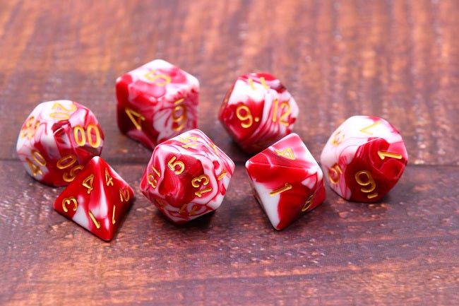 Lot de 7 dés multiformat en boîte – Cherry Cream – Jeu de rôle. Set rouge cerise et blanc crème effet marbré avec chiffres dorés (D4, D6, D8, D10, D00, D12, D20). Un design gourmand et raffiné parfait pour Donjons & Dragons, Pathfinder et autres jeux de rôle.
