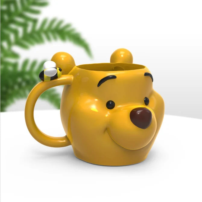 Mug Winnie l’Ourson 3D – 350 ml. Tasse en céramique représentant la tête de Winnie avec une abeille en relief sur l’anse.